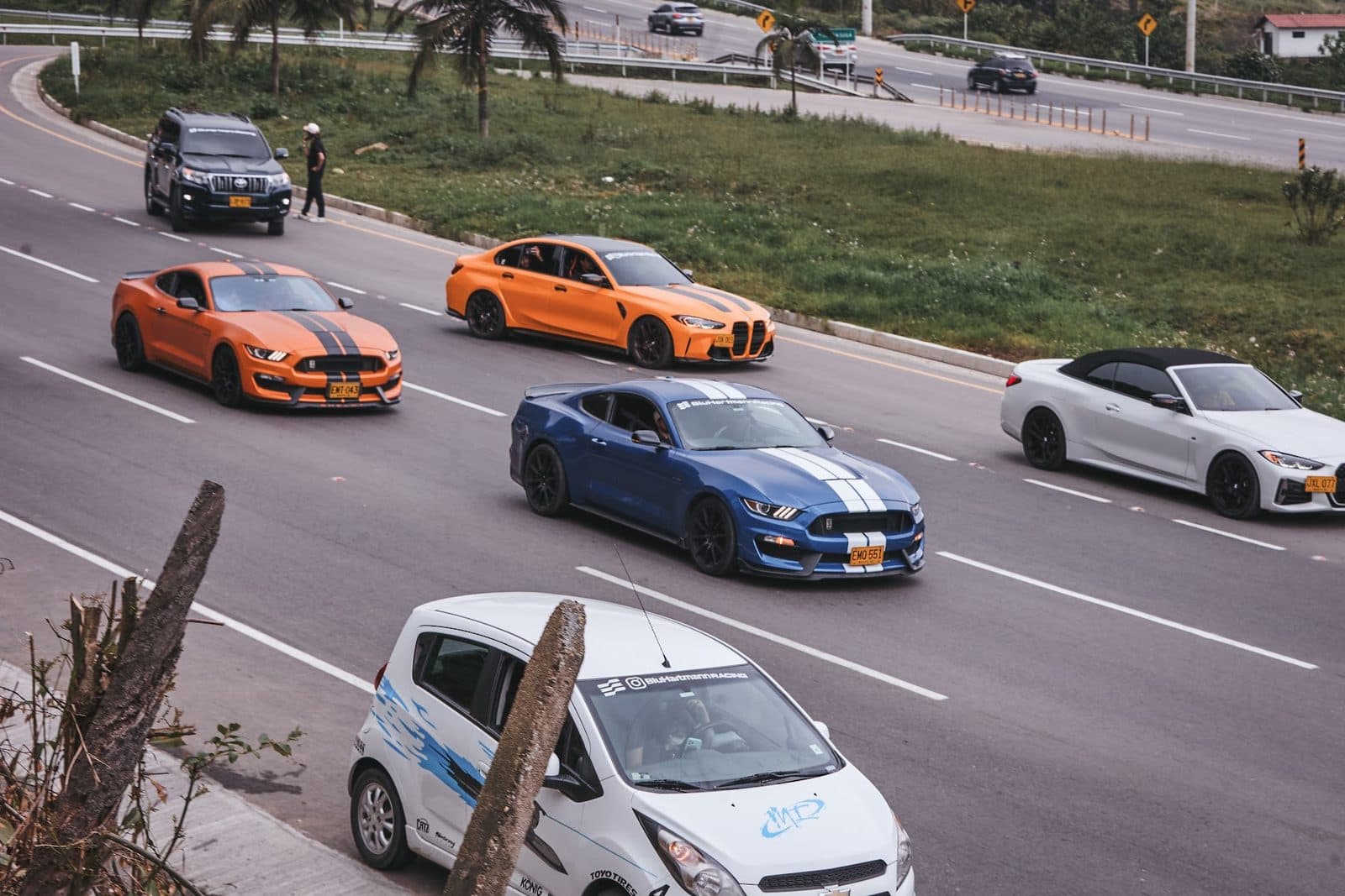 Mustangs y BMW naranjas en la rodada